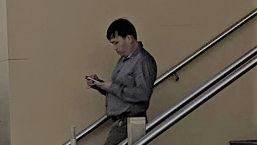 A man holding his phone and walking down the stairs outside a courthouse.