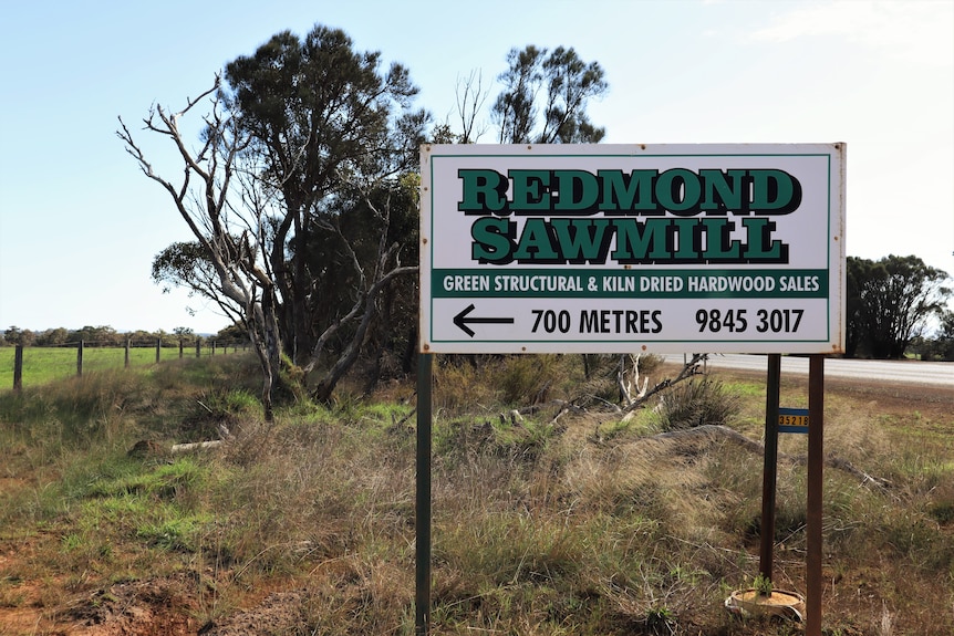 White sign with green writing that reads 'Redmond Sawmill'.