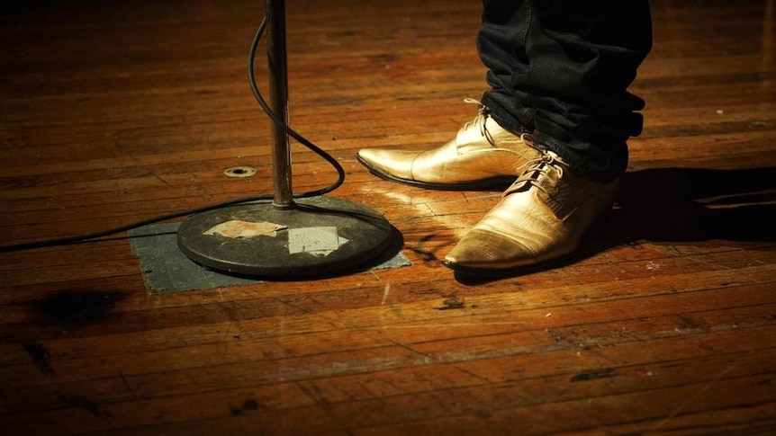 Picture of someone's gold shoes on stage