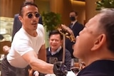 Salt Bae feeds a morsel of steak on a metal knife to To Lam in a restaurant. 