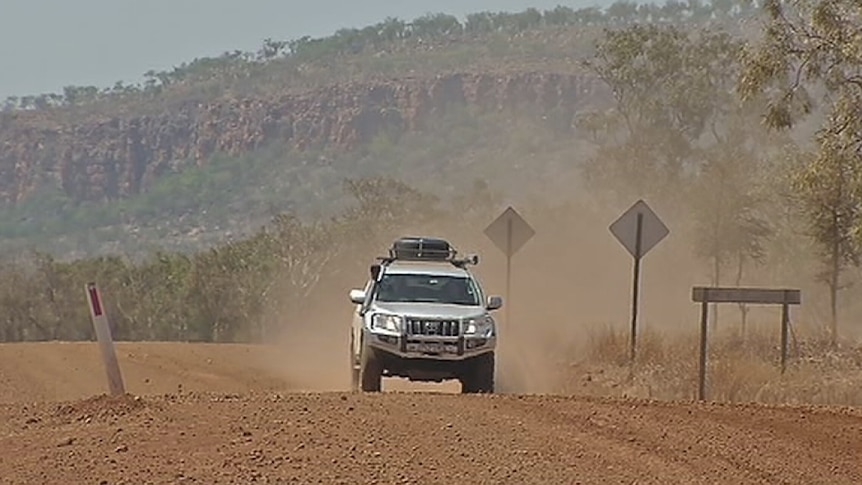 A 4 wheel drive vehicle on a gravel road.