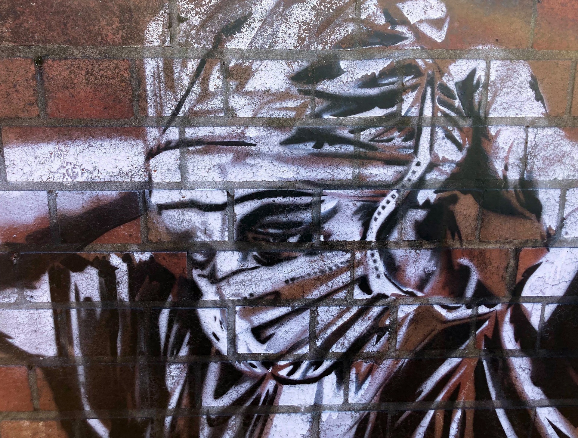 Stencil art on a brick wall depicting a healthcare worker strapping on a face mask