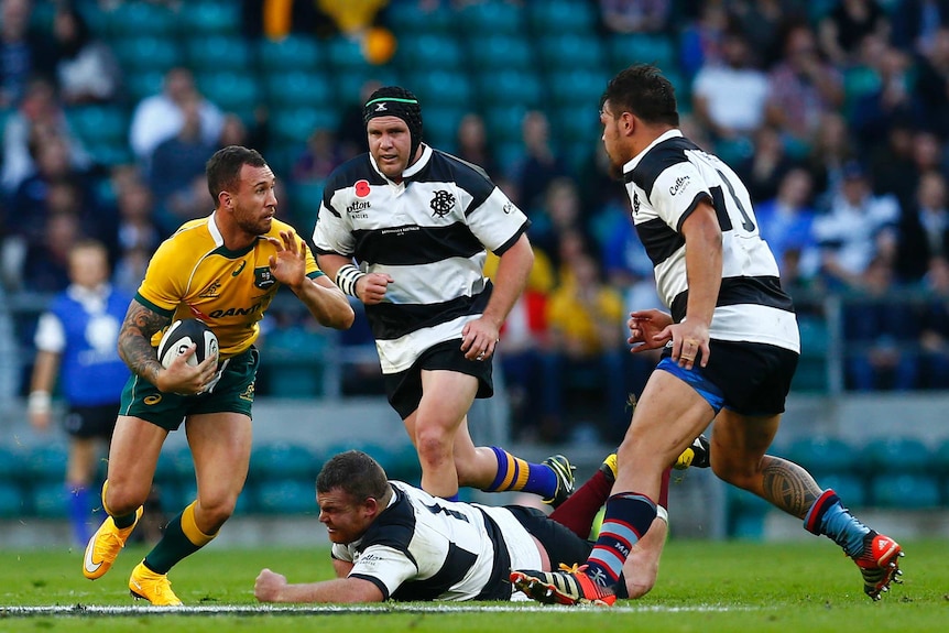Wallabies player Quade Cooper takes on three Barbarians defenders.