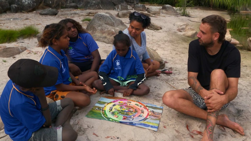 Indigenous children with adults and look at circular calendar