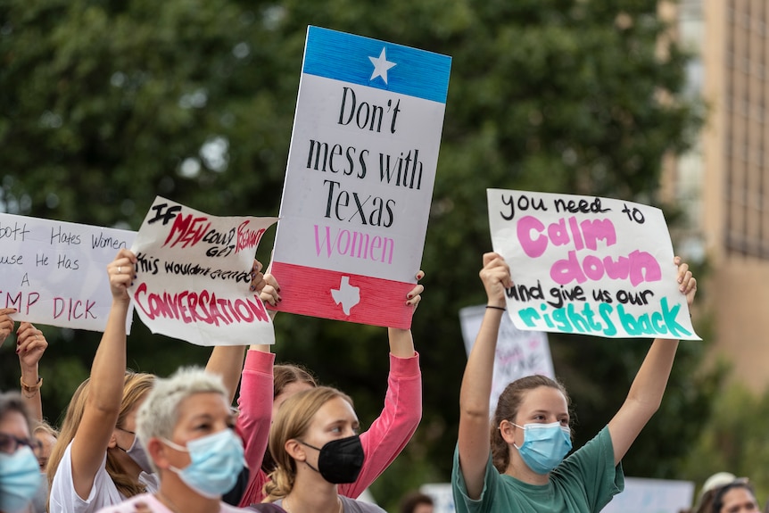 Women hold up signs at a protest against an abortion ban