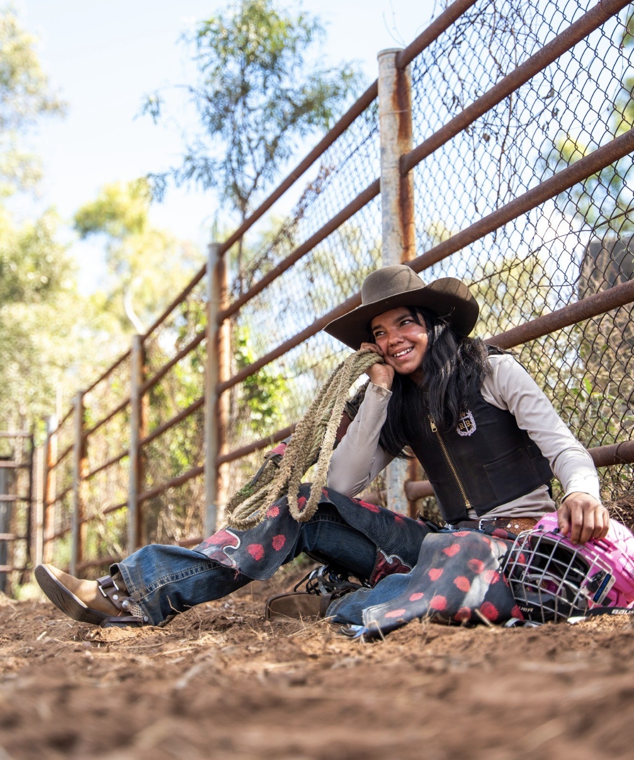 Lareece Daley-Kennedy sits smiling with a rope and pink riding helmet beside her.