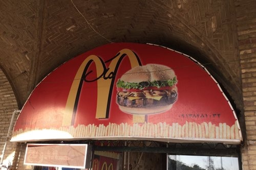 A storefront in Iran with a banner showing the golden arches of McDonalds and a burger.