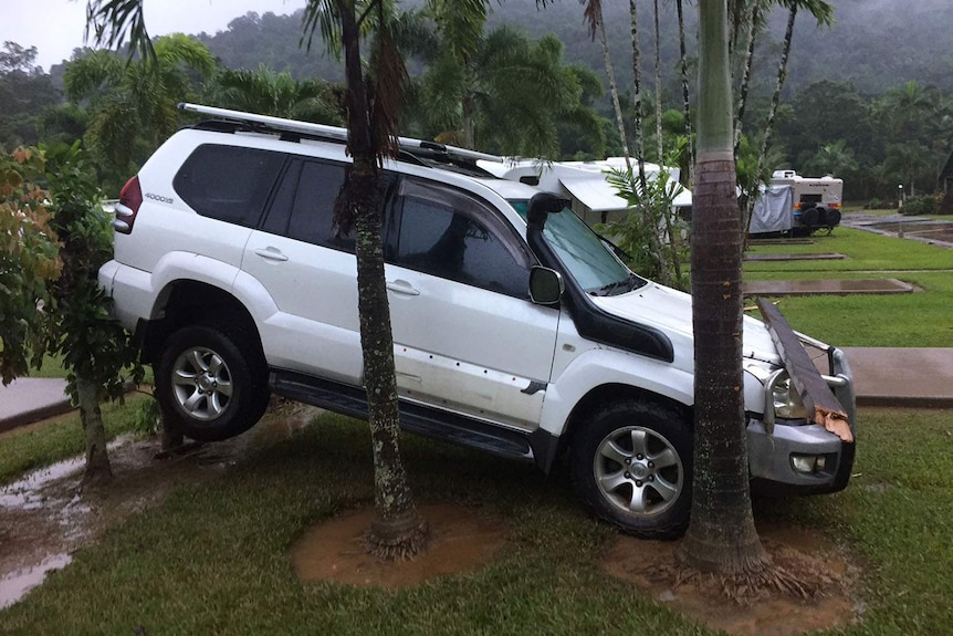 Damaged 4wd vehicle wedged against palm trees in a flooded caravan park in Cairns in far north Queensland on March 27, 2018.