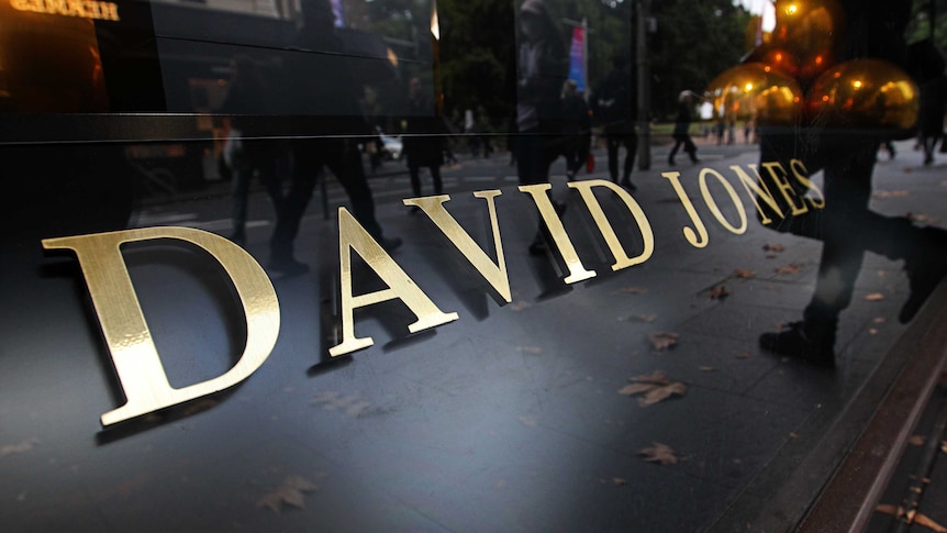 Close up of David Jones department store sign; gold letters on black background; reflection of passersby in the sign
