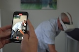 A physiotherapist films a patient wearing a VR unit.