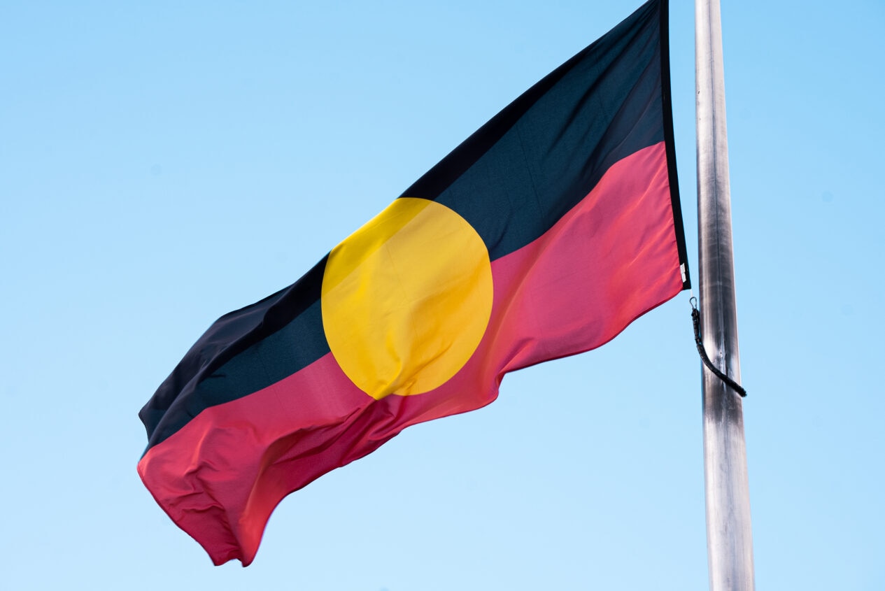 Una bandera aborigen ondea en el asta de la bandera en un día soleado 