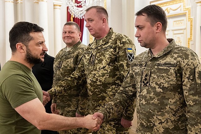 Volodymyr Zelenskyy shakes hands with men in uniform