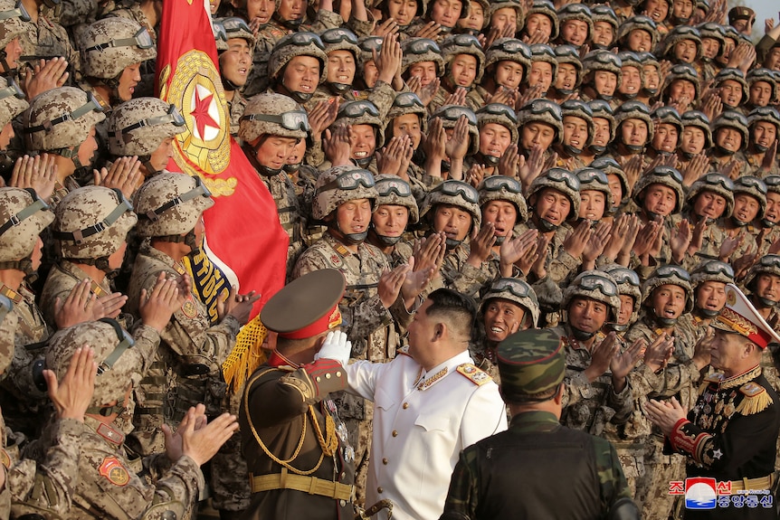 身穿白色夹克的金正恩站在一大群身穿制服的伞兵面前 