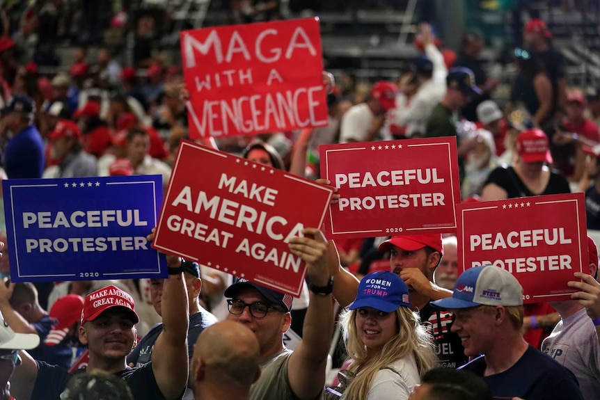 Supporters wait for President Donald Trump with "peaceful protester" sign