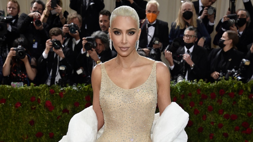 kim kardashian in a gold sequinned gown and white blonde hair on the red carpet