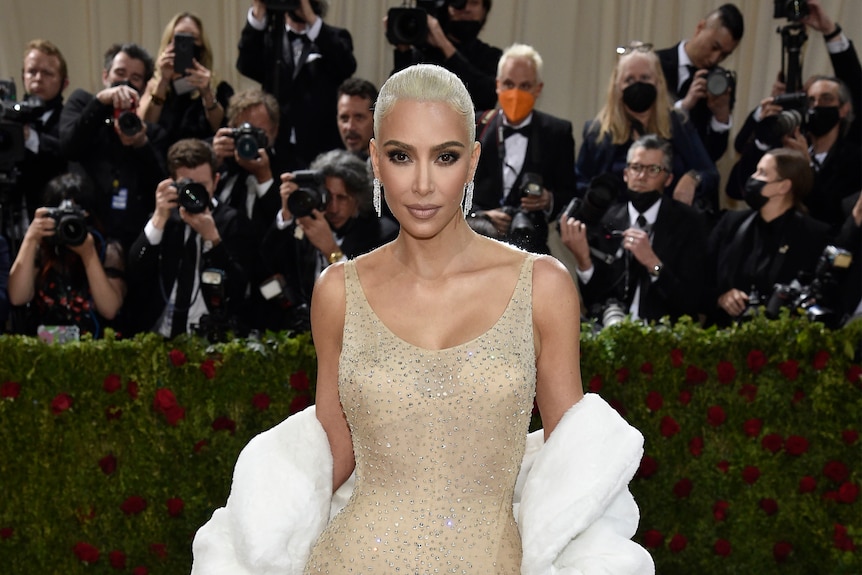 kim kardashian in a gold sequinned gown and white blonde hair on the red carpet