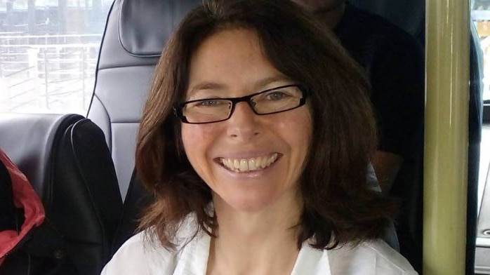 A woman sitting on a bus and smiling.