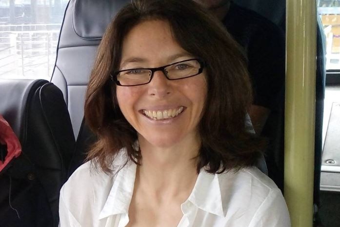 A woman sitting on a bus and smiling.