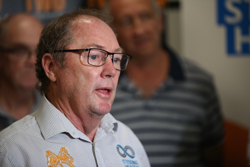 A side view of Mr Dawson as he is speaking while wearing a white collared shirt and glasses