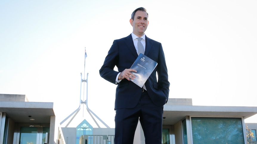 Jim Chalmers holds the budget while standing outside Parliament House