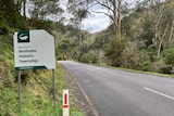 Walhalla town sign on a road ringed with green hills.