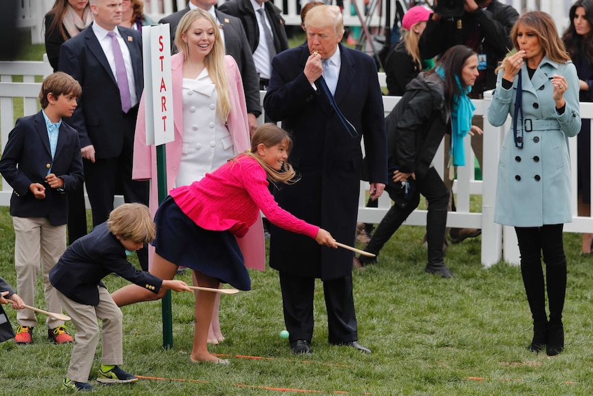 US President Donald Trump and First Lady Melania Trump blow whistles to start a game at the annual White House Easter Egg Roll.