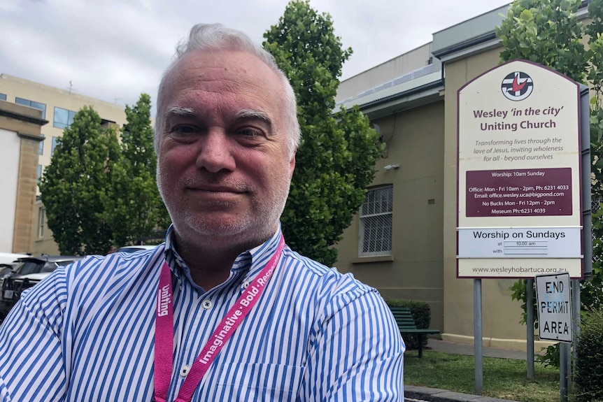 A man smiles and crosses his arms outside a Uniting church.