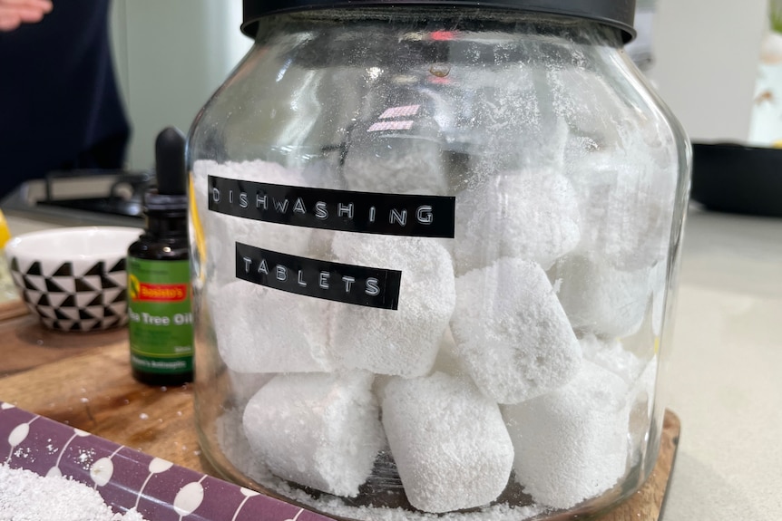 A glass jar containing dishwashing tablets with the words "dishwashing tablets" written on the outside