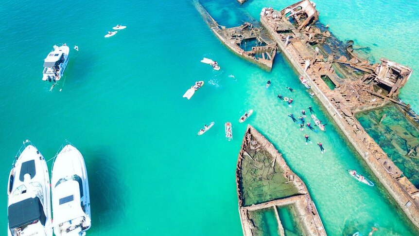 A drone photo of smaller boats around a shipwreck.