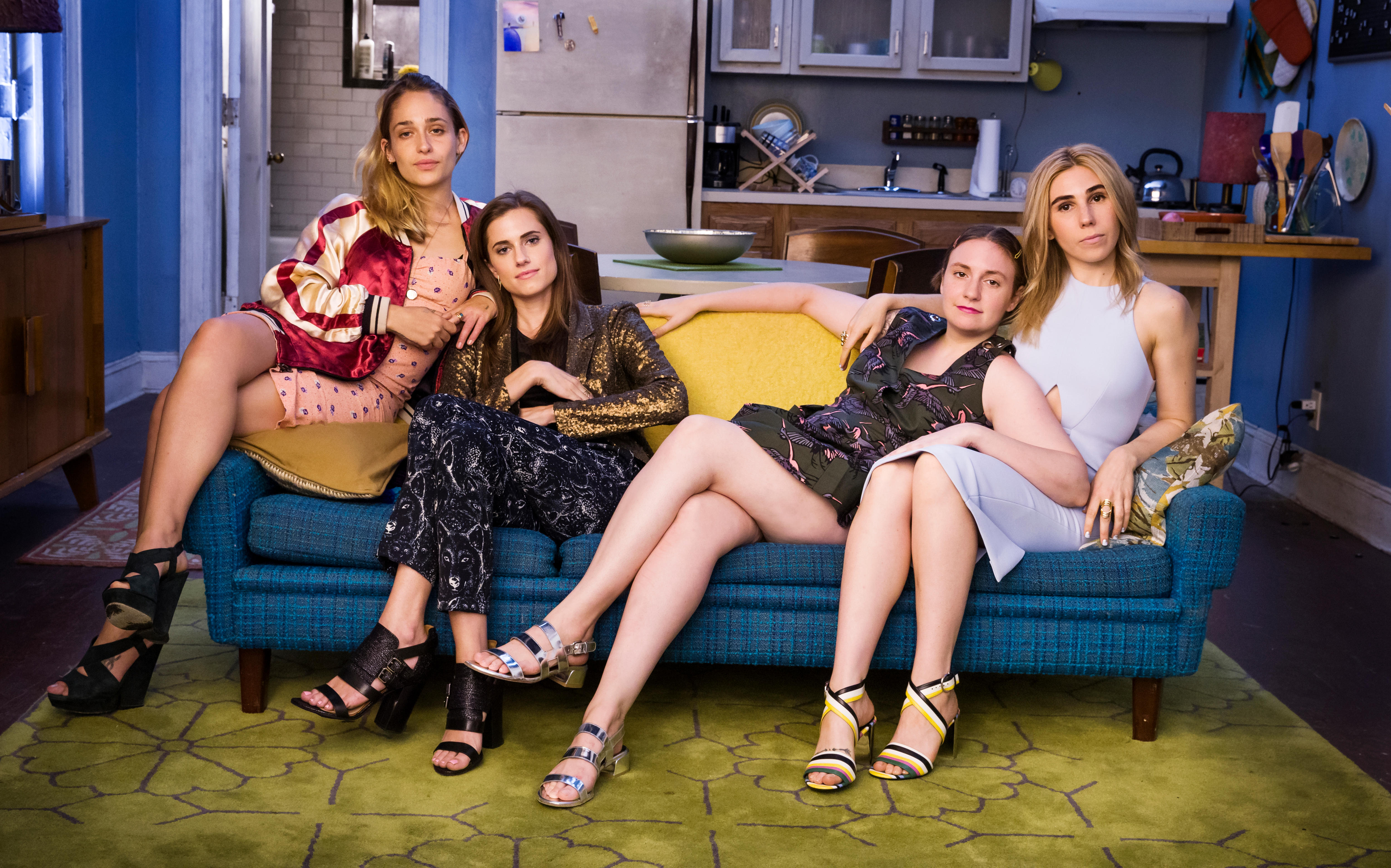 Four young women lying and sitting on a lounge in fancy dresses and strappy shoes