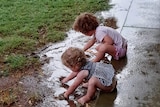 Two girls play in puddles.