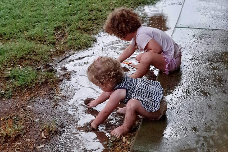 Two girls play in puddles.