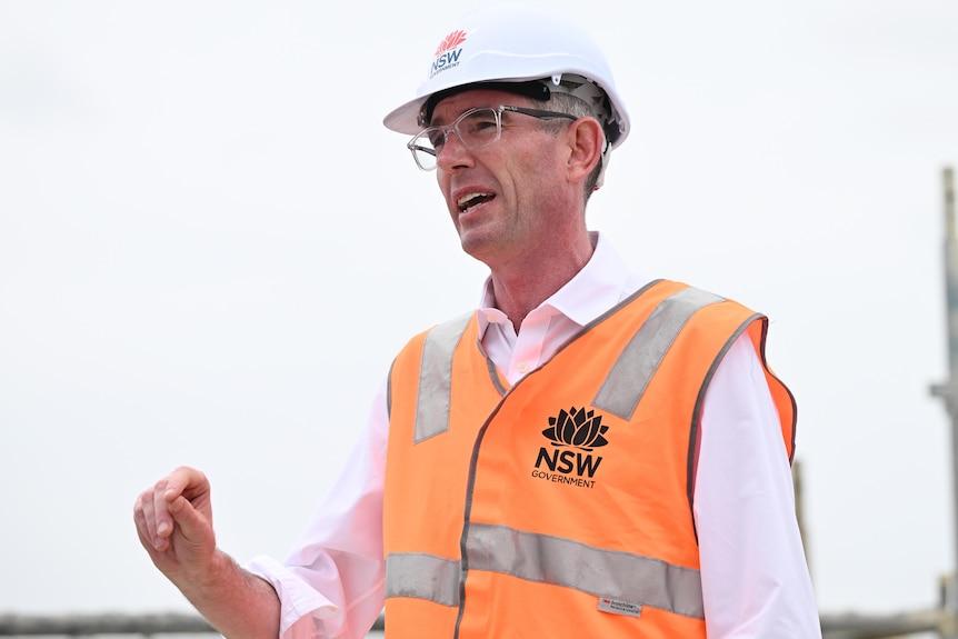 a man wearing glasses and a hard hat speaking outdoors