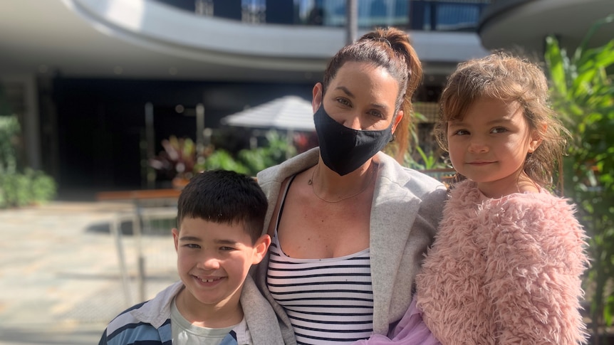 Mother in a mask and her two kids standing together
