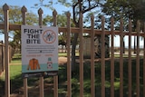 a sign reading "FIGHT THE BITE" tied to a fence in Port Hedland.
