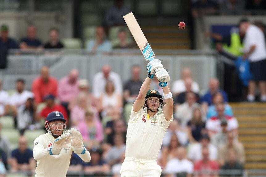 Australia batsman Steve Smith's bat is pointed up in the air as he tries to hit a ball way above his head.