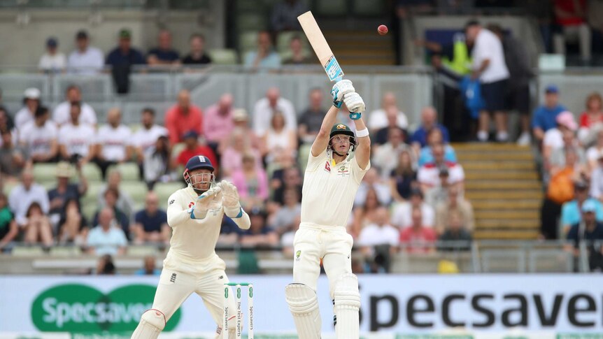 Australia batsman Steve Smith's bat is pointed up in the air as he tries to hit a ball way above his head.