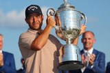 Xander Schauffele holds up a lare silver trophy