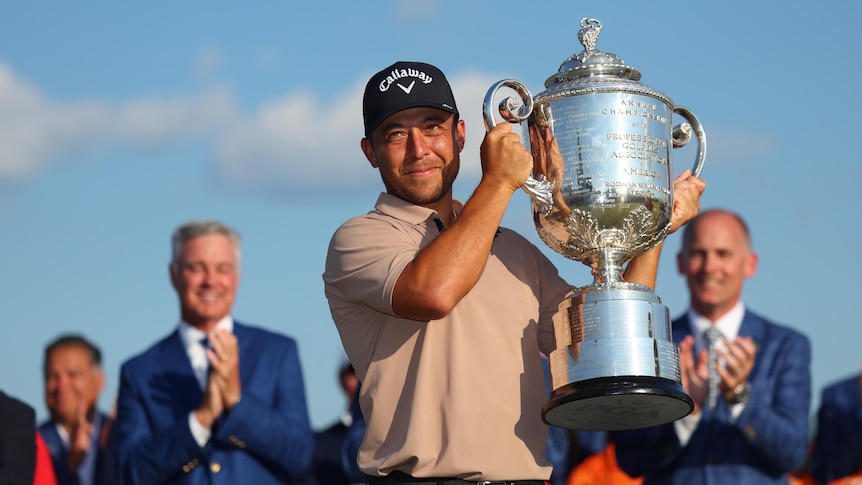 Xander Schauffele holds up a lare silver trophy