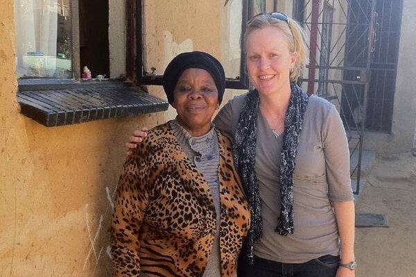 Two women stand together smiling at the camera.