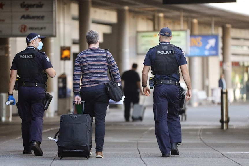 A man walks with police at the the Brisbane airport.