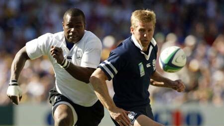Rupeni Caucau of Fiji kicks ahead of Glenn Metcalfe of Scotland
