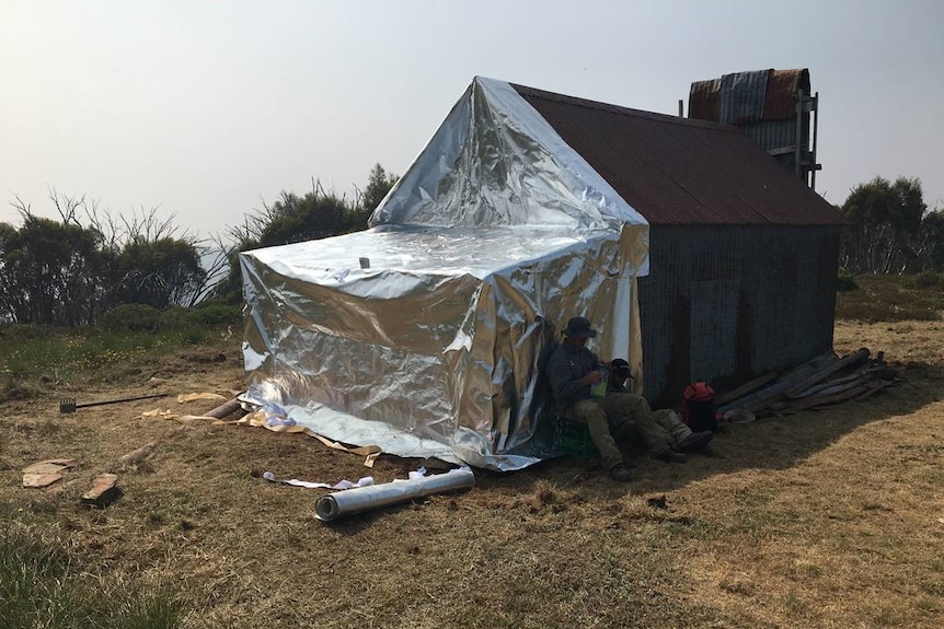 An old hut is wrapped in silver foil.