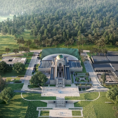 An aerial image of the war memorial with an extension on the back. It sits below a tree-filled mountain