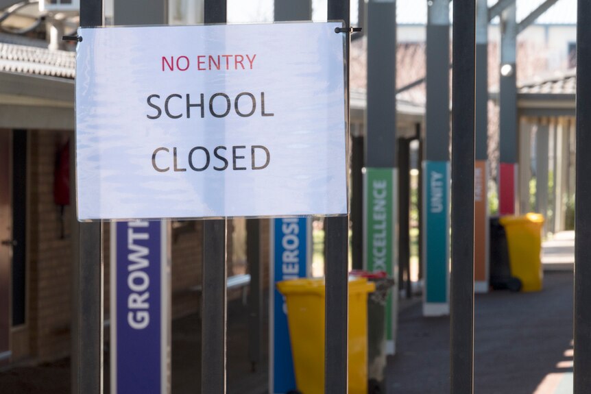 A sign saying 'no entry school closed' pinned up at the front of a school