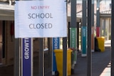 A sign saying 'no entry school closed' pinned up at the front of a school