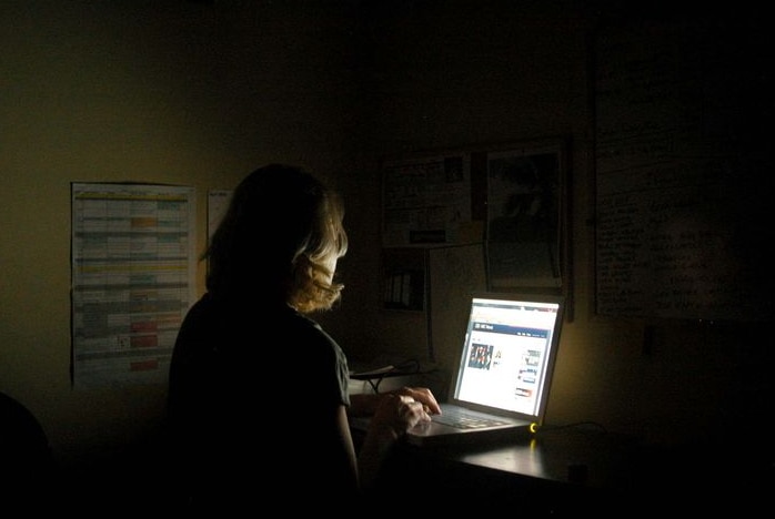 A woman works at her laptop computer late into the night