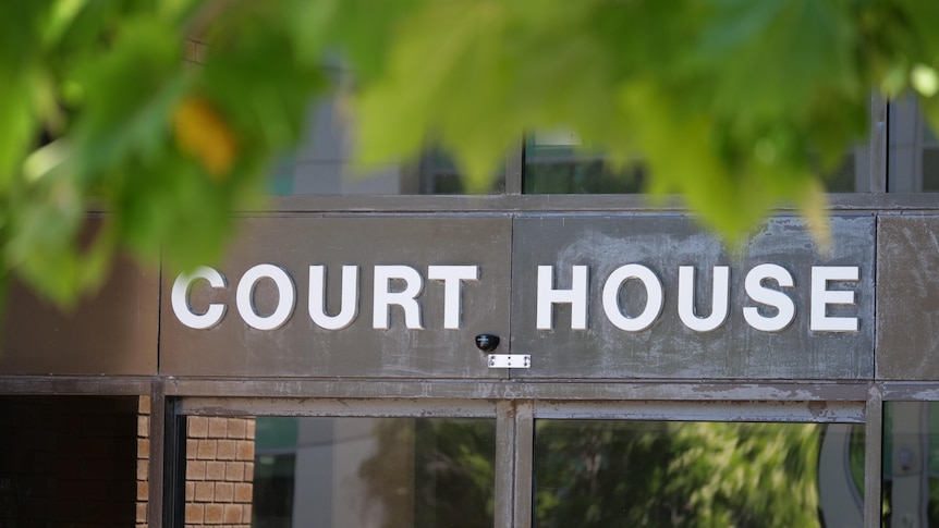 Lettering that reads "Court House" on a drab metal door.