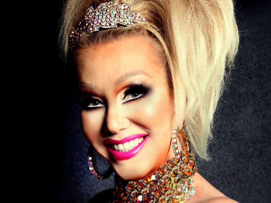 Transgender woman with blonde hair, a tiara and stage makeup. 