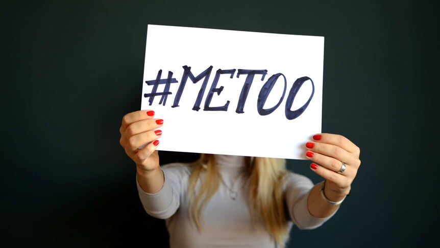 A woman holds a sign with the words #MeToo.